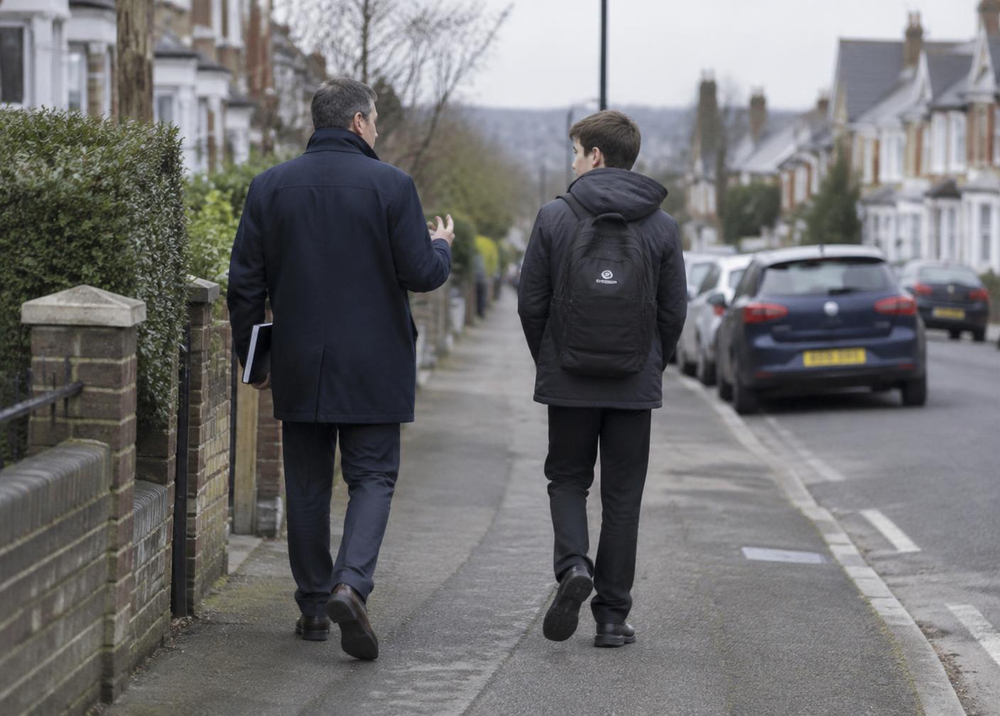 A practitioner and a young person walking and talking on a quiet residential street